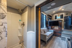 Ein modernes Interieur mit Dusche, Sofa, Fernseher und Küchenzeile.