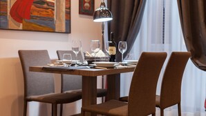A dining table set with wine glasses, plates, and cutlery, with a lamp and a painting on the wall.