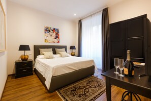 A neatly arranged bedroom with a bed, bedside tables, a desk, and a bottle of champagne. - ROME BOUTIQUE APARTMENTS comfortable, cozy, central, 8minutes from the vatican (Roma)