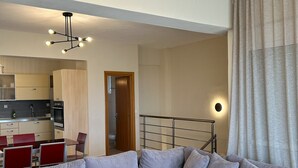 Een moderne woonkamer met een modulaire bank, een houten salontafel en een eethoek met rode stoelen.