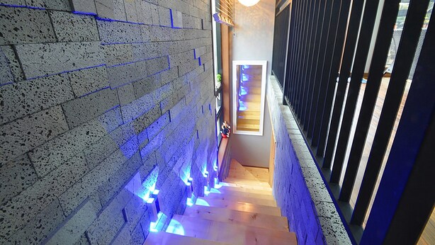A staircase with a textured wall and blue lighting. - NonilSO Private Pension (Seogwipo)