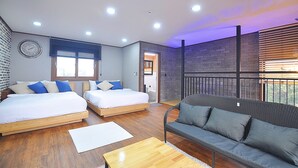 A modern bedroom with two beds, a sofa, and a balcony with a view. - NonilSO Private Pension (Seogwipo)