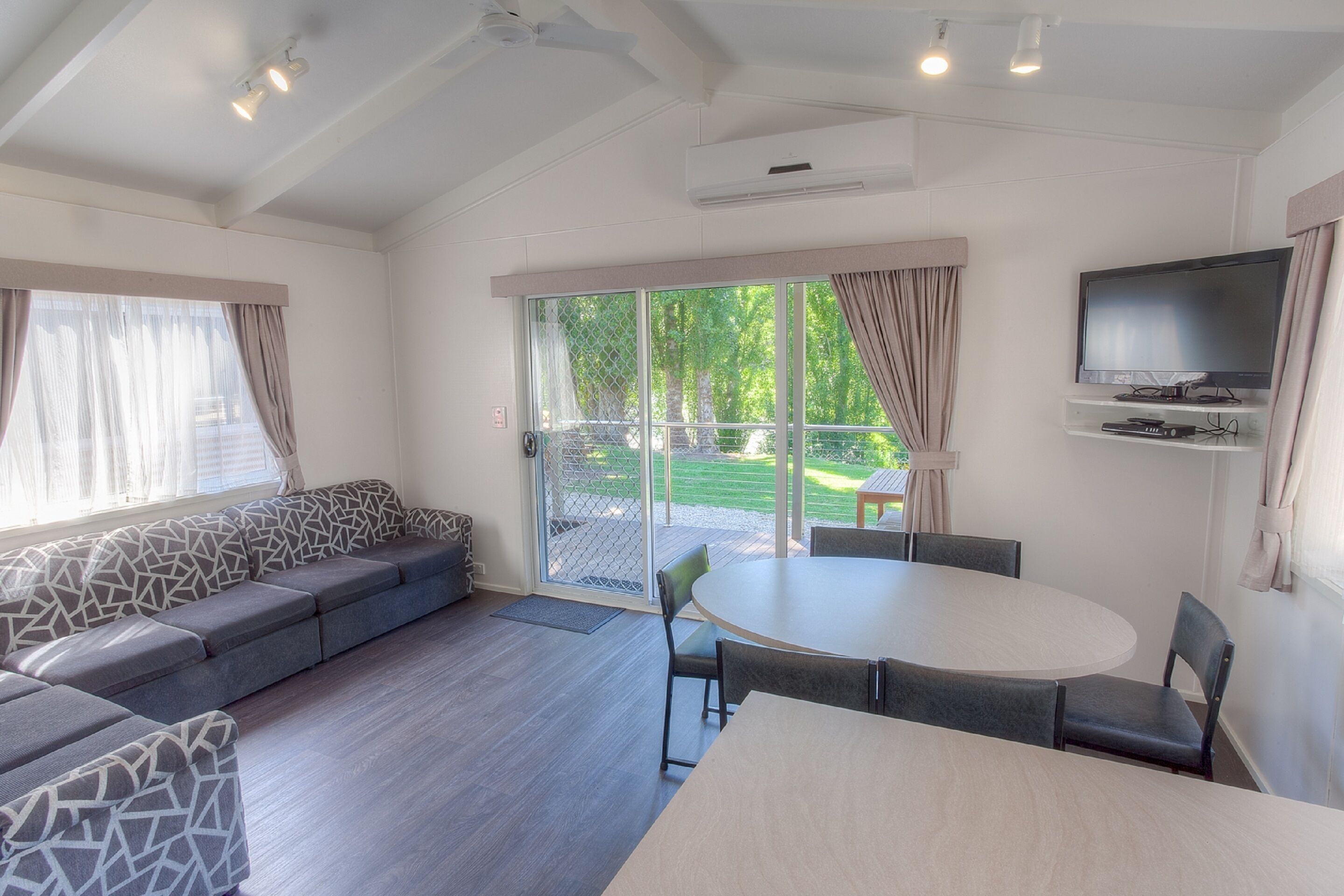 A modern living room with a sofa, a round table, and a TV mounted on the wall.