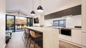 A modern kitchen with a large island, bar stools, and a view of the outdoors. - Bright Riverside Holiday Park (Bright)