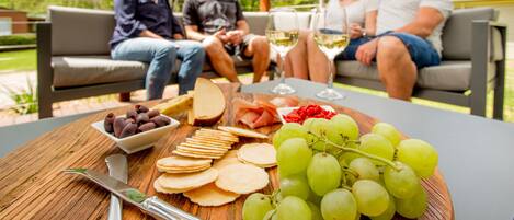 A wooden table with a cheese board, grapes, crackers, and a knife.