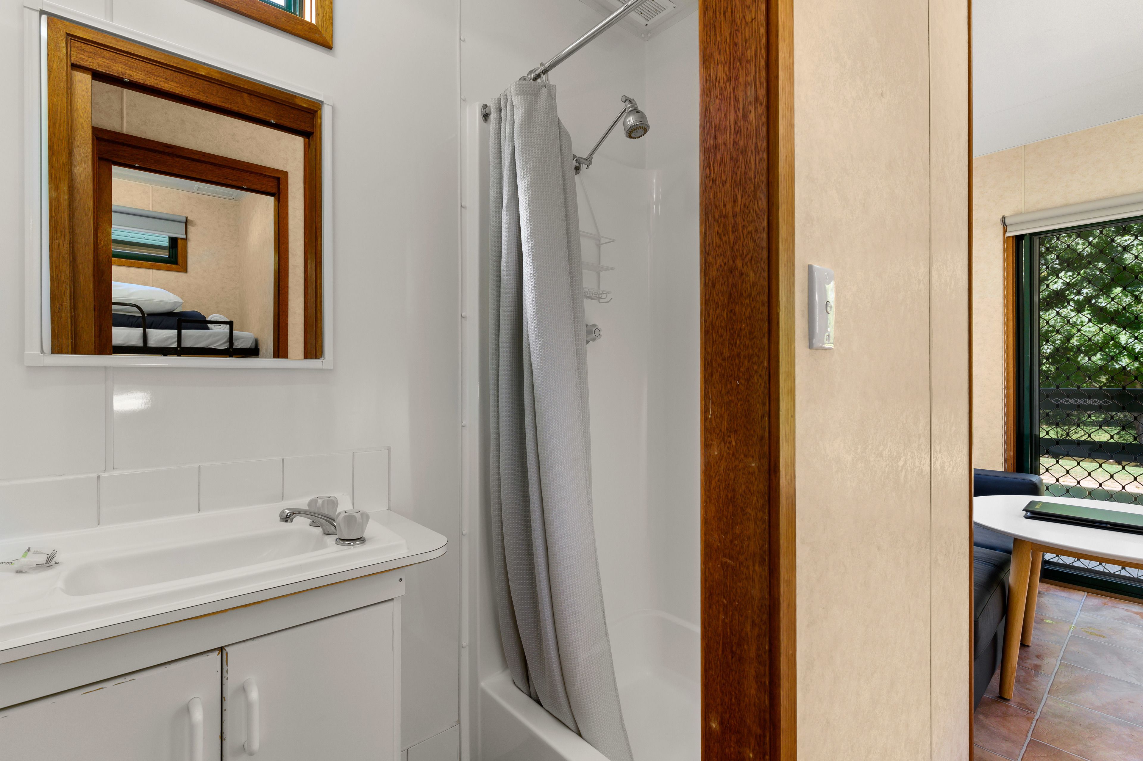 Un baño con ducha, lavamanos y espejo.
