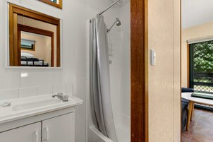Un baño con ducha, lavamanos y espejo.