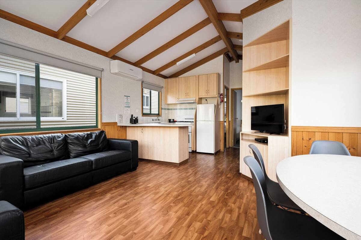 A modern kitchen with wooden cabinets, a built-in stove, and a dining area with a table and chairs.