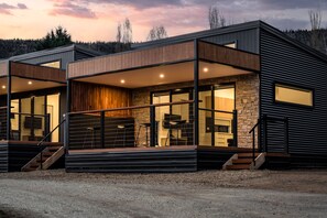 A modern two-story house with a stone facade, large windows, and a balcony.
