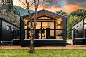 A modern house with a large glass front, wooden deck, and stone walls.