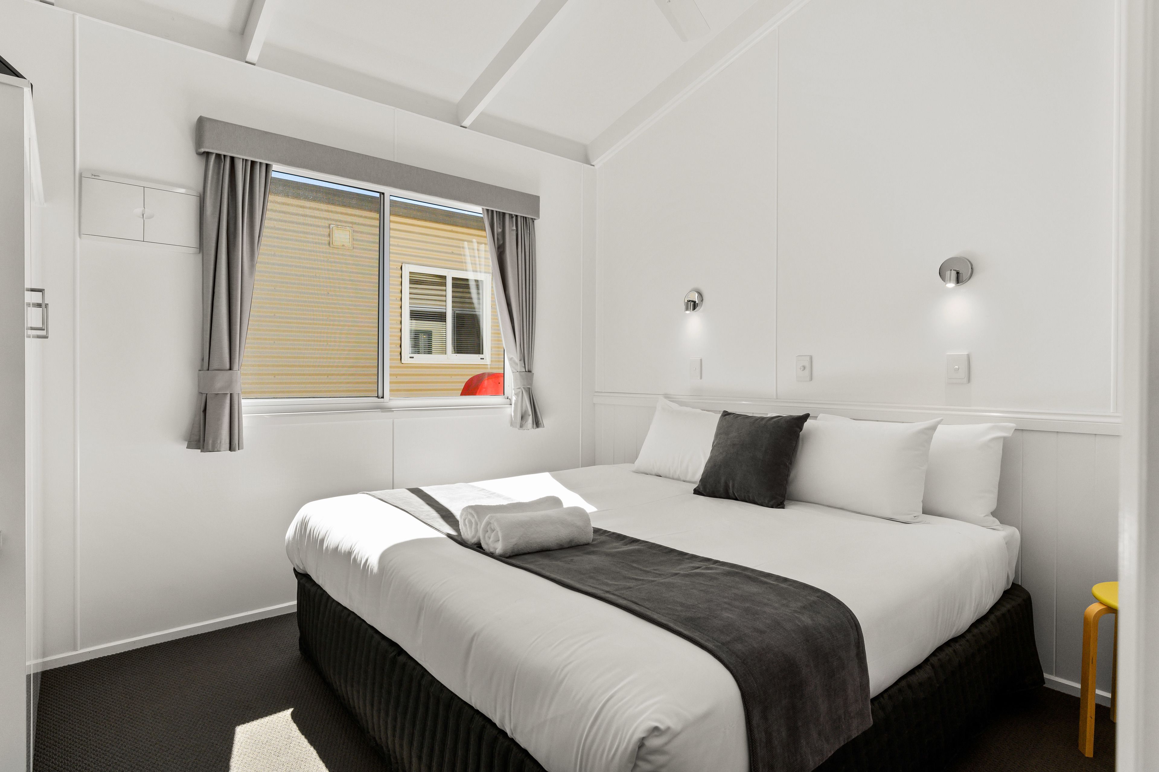 Une chambre d’hôtel moderne avec un grand lit, une fenêtre avec des rideaux et une vue sur un bâtiment à l’extérieur.