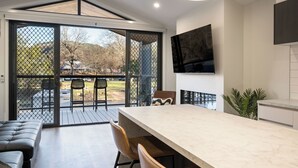 A modern kitchen with a large island, sliding glass doors to a deck, and a flat-screen TV mounted on the wall. - Bright Riverside Holiday Park (Bright)