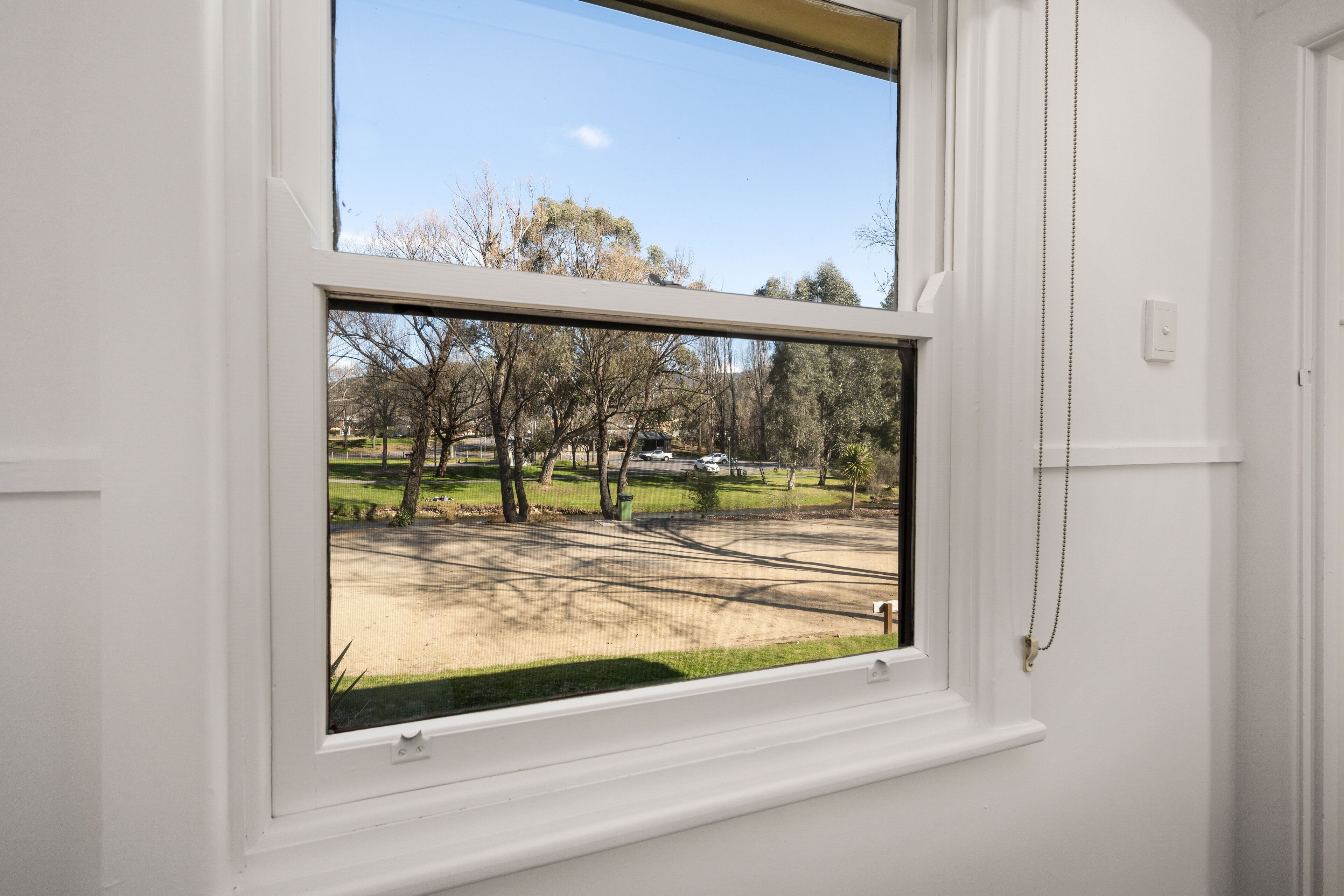 Una ventana con vista a un parque y una calle.