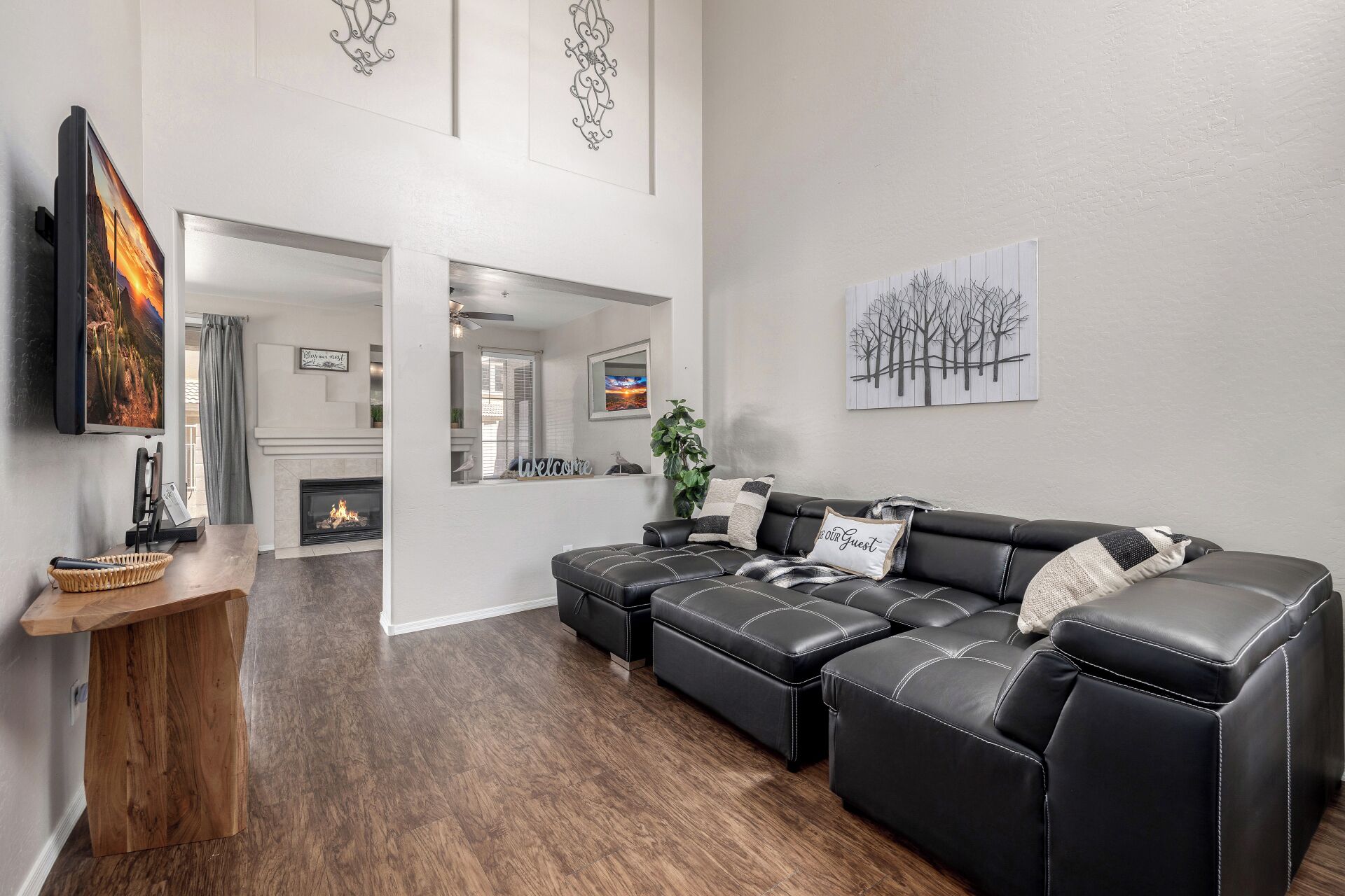 A modern living room with a sectional sofa, a fireplace, and artwork on the walls.