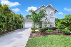 Stunning two-story home with a covered porch, lush garden, and driveway.