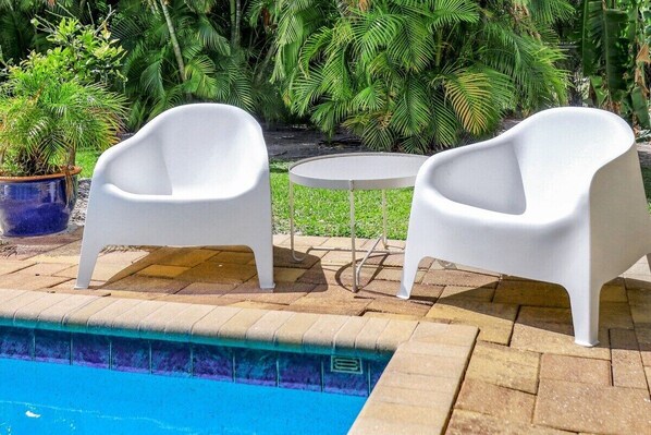 Relax by the pool surrounded by lush greenery and tropical plants.