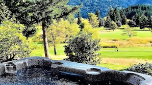 A hot tub with a view of a golf course and mountains in the background. - Movie Theater! Hot Tub! Private Rental 3 Bedrooms and 2 Bathrooms. (Bellingham)