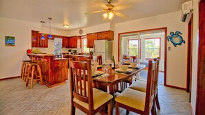 A spacious kitchen with wooden cabinets, a dining area with a large table and chairs, and a ceiling fan.