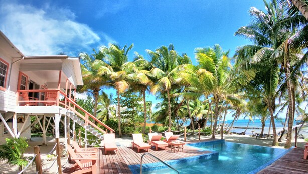 A wooden deck with a pool, lounge chairs, and a view of the ocean.