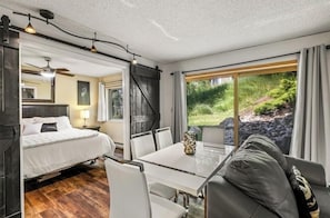 A bedroom with a bed, a bedside table, and a window with curtains.