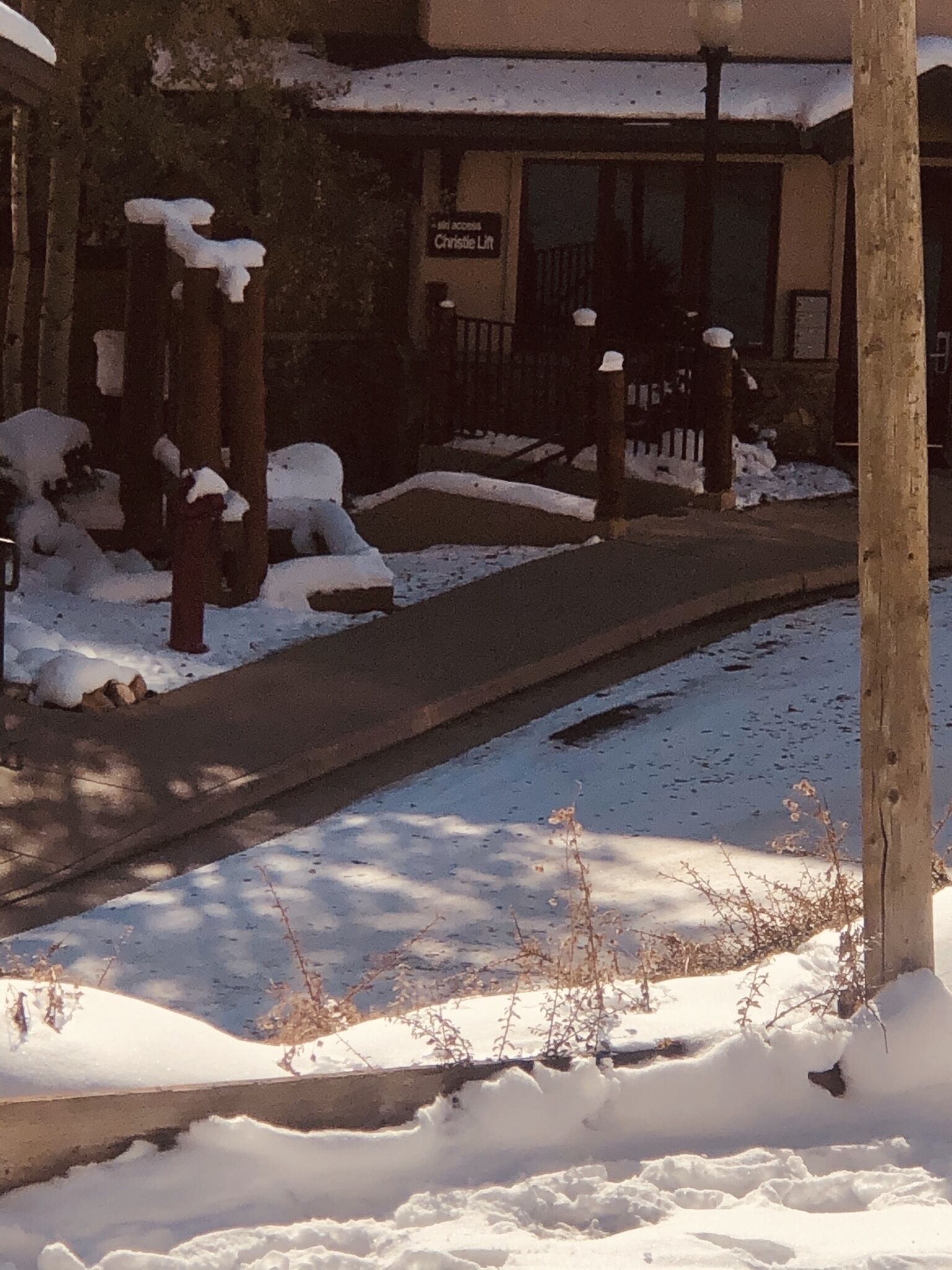 A snow-covered sidewalk leading to a building with a sign reading "Christie Lift."