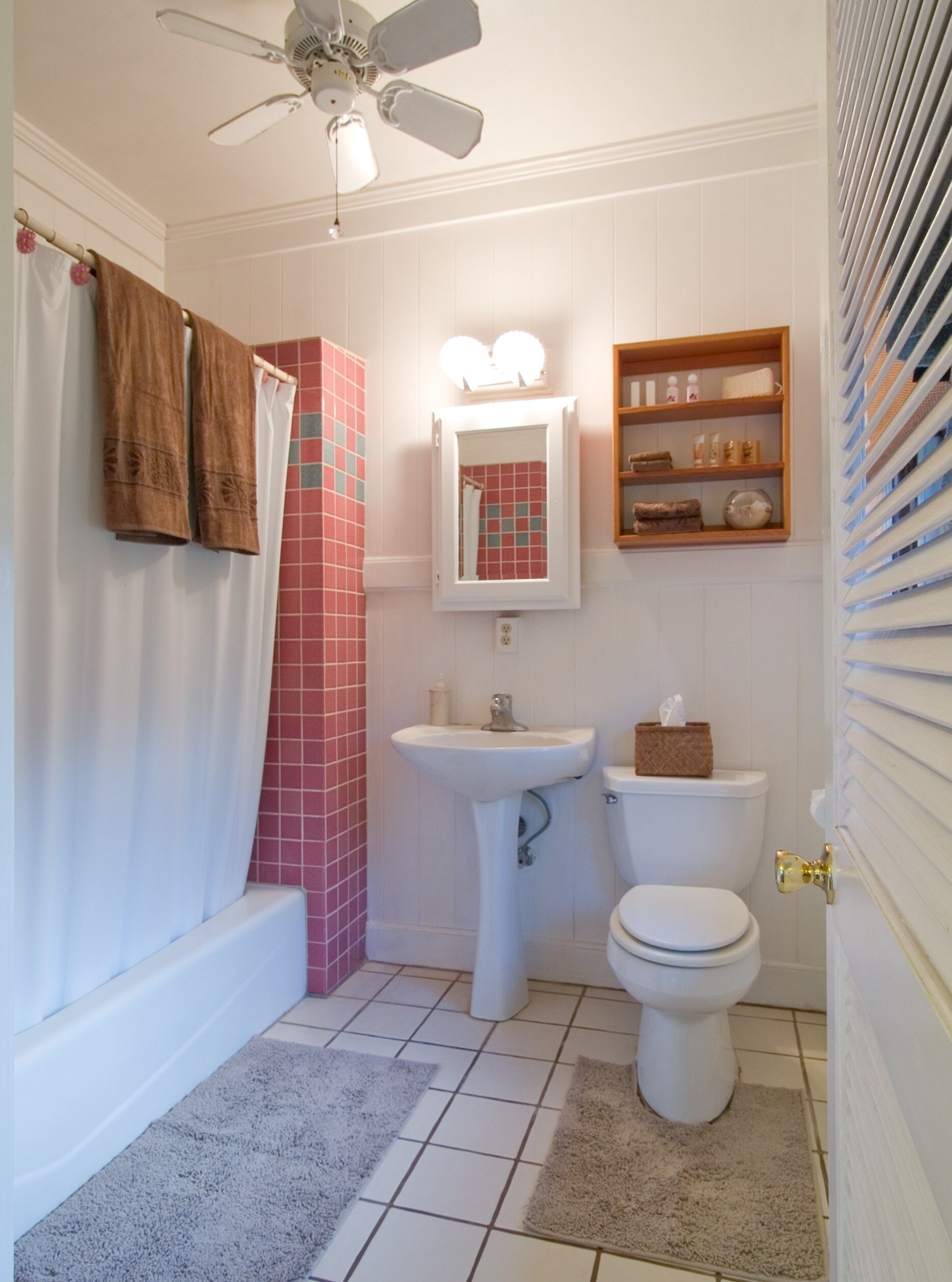 A bathroom with a bathtub, toilet, sink, and a ceiling fan.