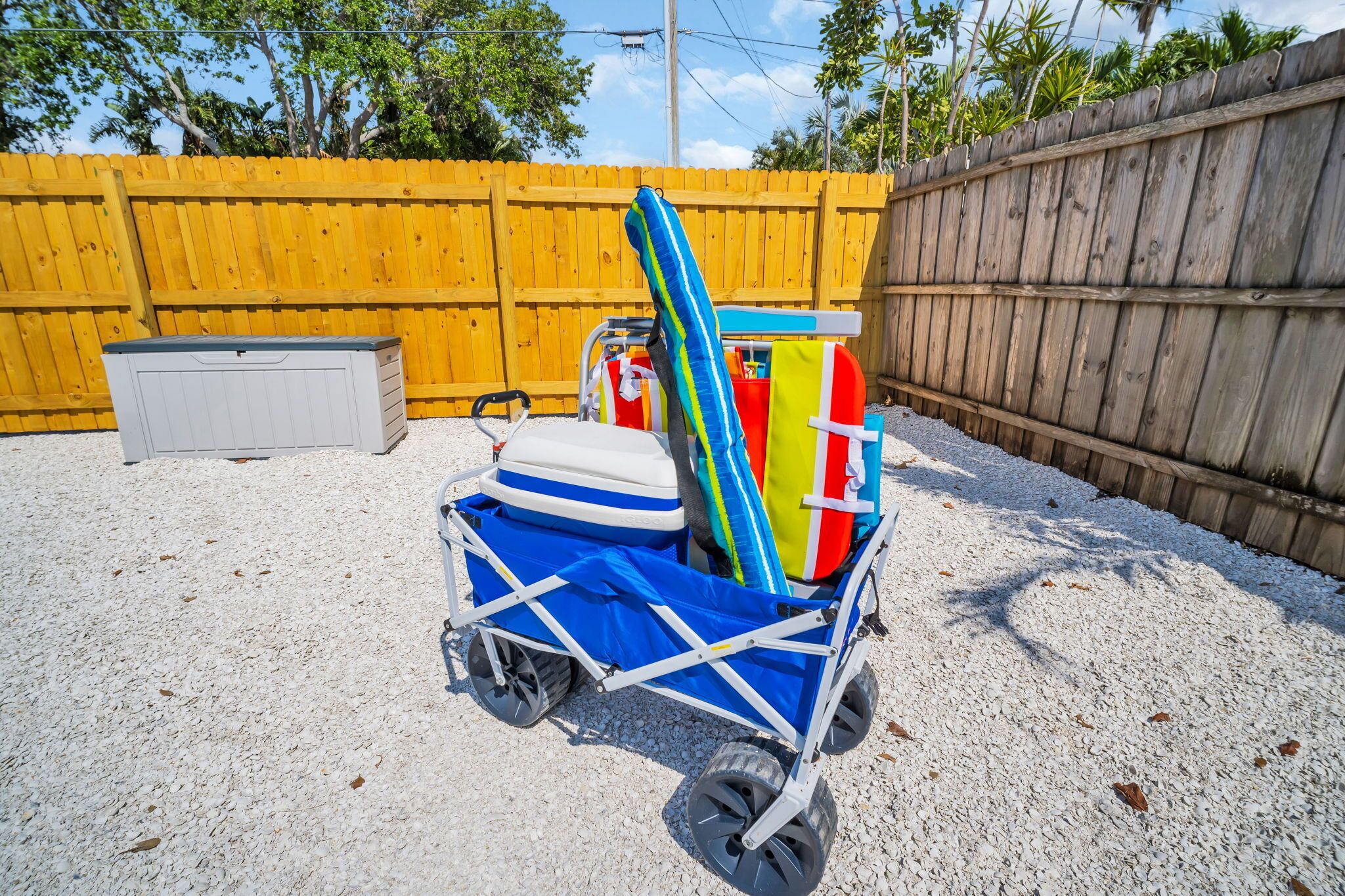 Ein Strandkorb mit einer blauen und weißen Kühlbox, einem gestreiften Handtuch und einer roten und gelben Rettungsweste.