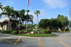 A landscaped area with a fountain, palm trees, and a building with a circular window.