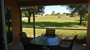 Eine Terrasse mit Tisch und Stühlen mit Blick auf einen Golfplatz.