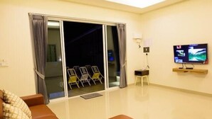 Ein Hotelzimmer mit Sofa, Fernseher, einer Schiebetür und Blick ins Freie.