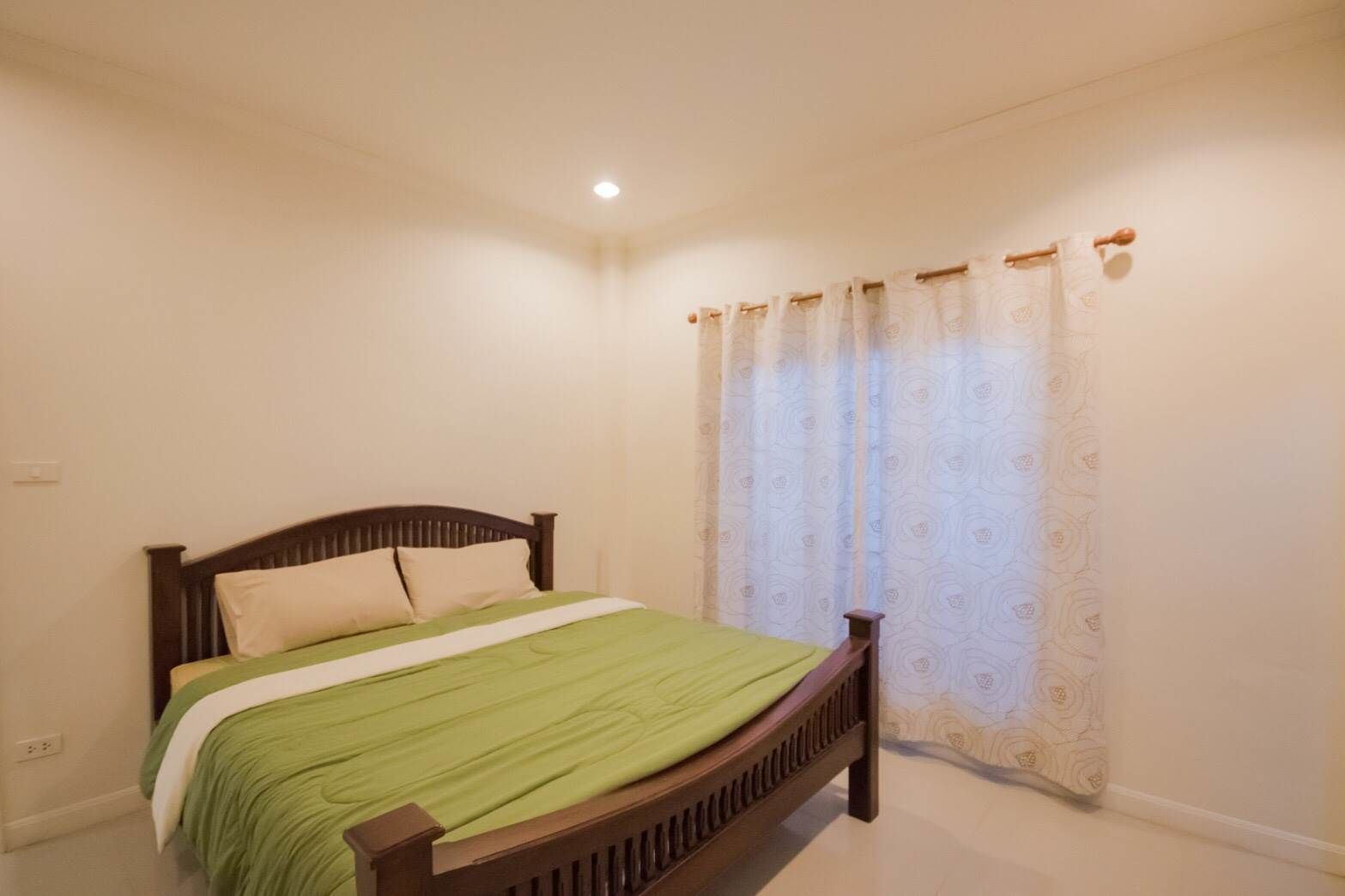 Une chambre à coucher avec un lit simple, une tête de lit en bois et un rideau à motifs.