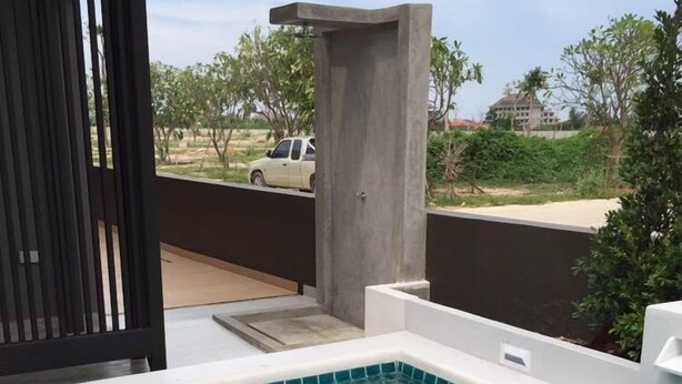 Ein rechteckiger Swimmingpool mit klarem, blauen Wasser, umgeben von einer weißen Liegefläche und einem schwarzen Geländer.