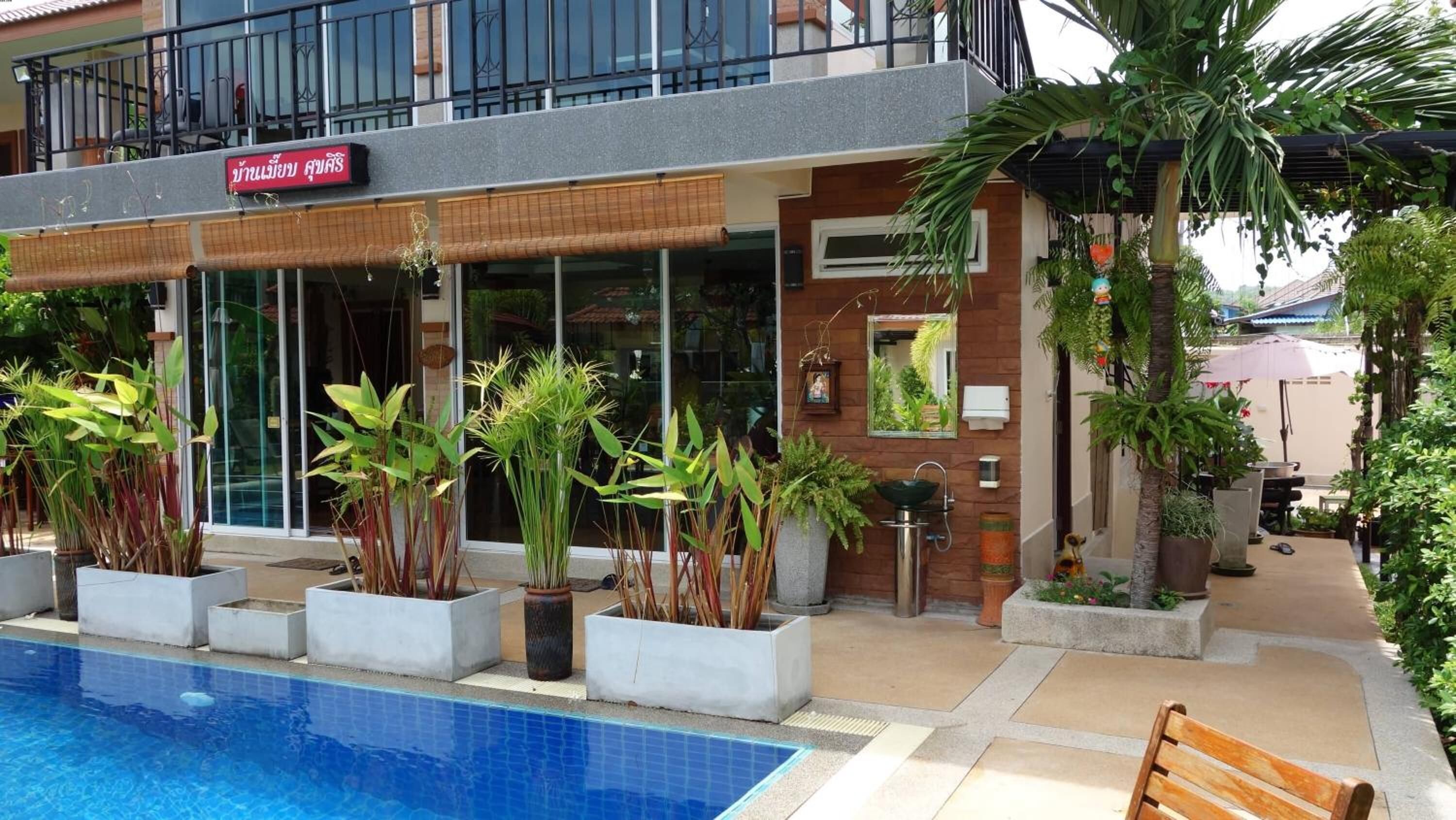 A hotel with a pool, potted plants, and a sign in a foreign language.