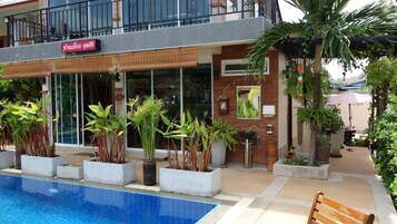 Un hôtel doté d’une piscine, de plantes en pot et d’une enseigne dans une langue étrangère.