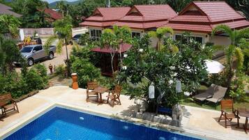 A residential area with a swimming pool, patio furniture, and a car parked nearby.