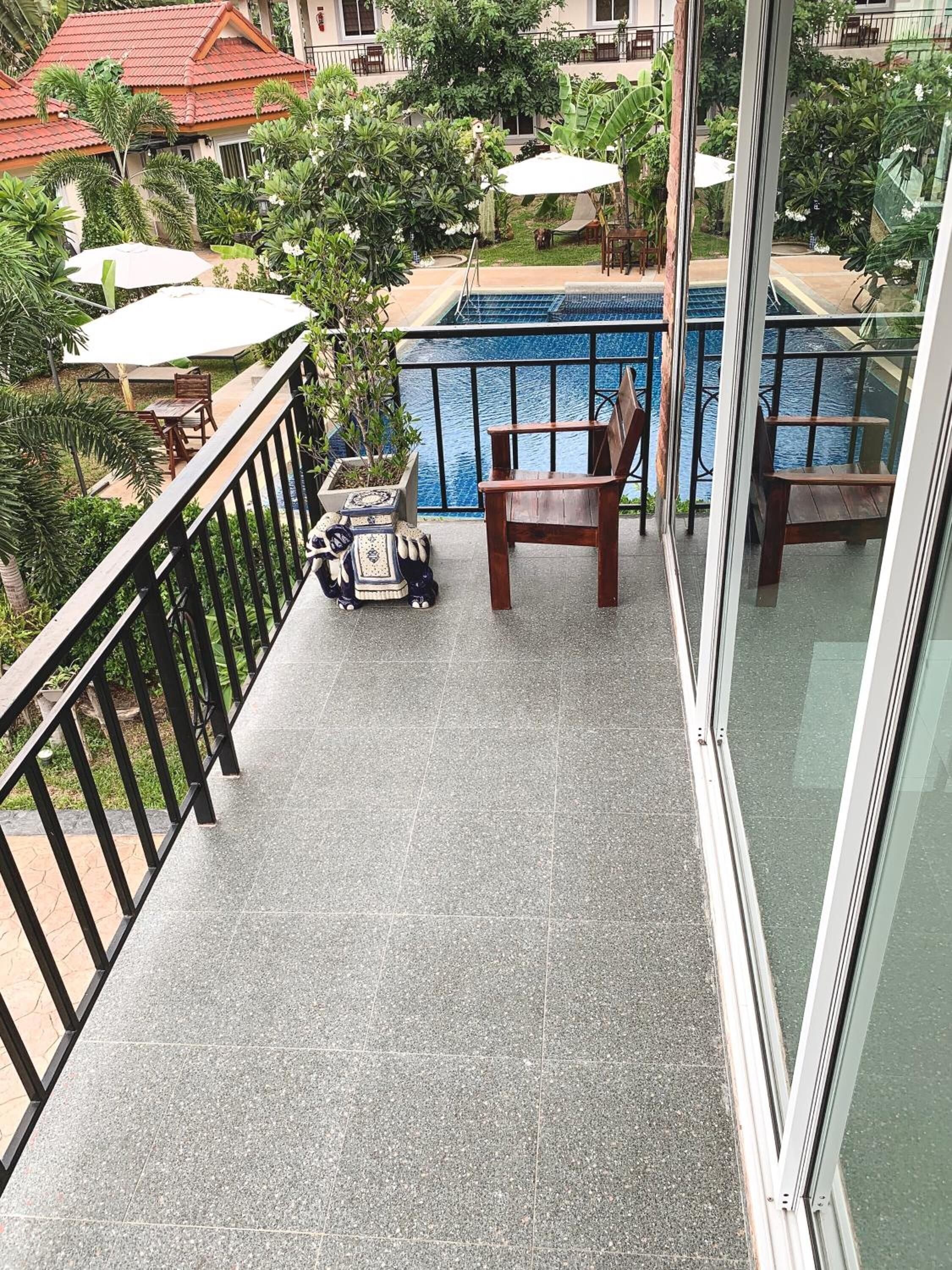 A balcony with a pool, outdoor furniture, and lush greenery.