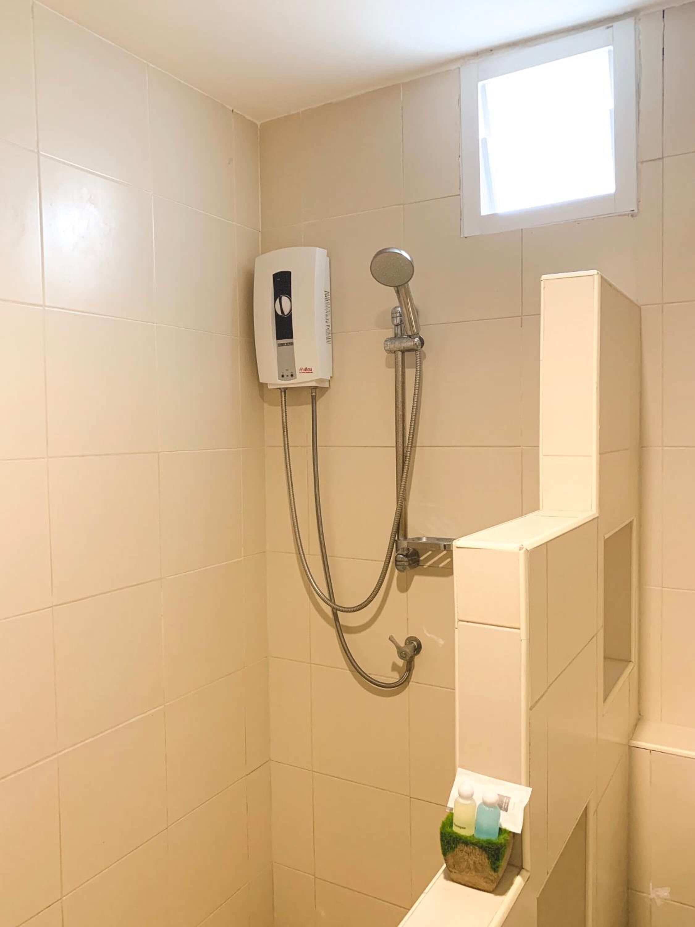 Une douche équipée d’un pommeau de douche à main et d’un panneau de commande fixé au mur.