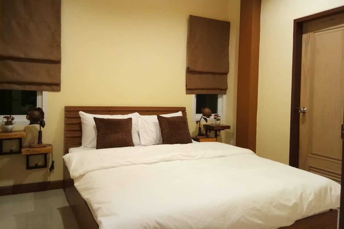 Une chambre d’hôtel avec un grand lit, une tête de lit en bois et des rideaux marron.