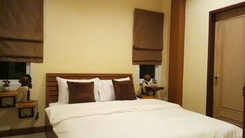 Habitación de hotel con una cama grande, cabecero de madera y cortinas marrones.