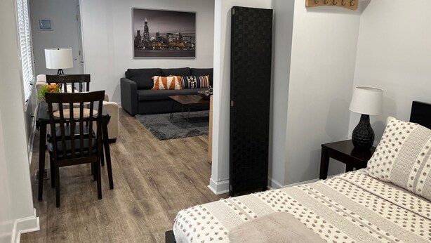 Ein modernes Schlafzimmer mit einem Bett, einem Nachttisch, einer Lampe, einem Holzregal und einem Stadtbild an der Wand.