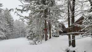 Una carretera cubierta de nieve con un vehículo estacionado junto a un edificio.
