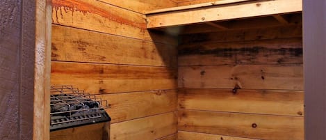 A wooden interior with a built-in stove and a shelf.