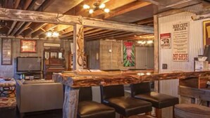 Un rústico espacio de bar con vigas de madera, mostrador y asientos.