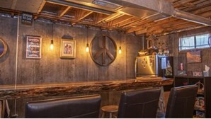 Un rústico espacio de bar con paredes de madera, una barra y asientos.