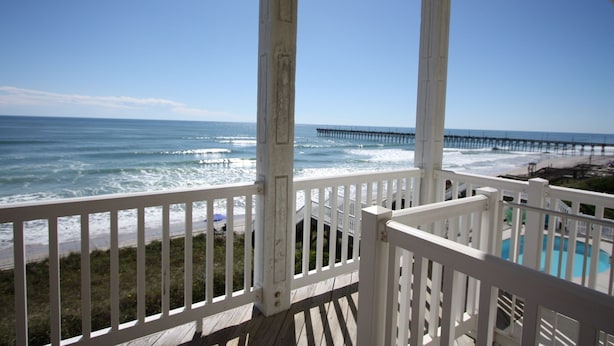 A wooden deck with a view of the ocean and a pier.
