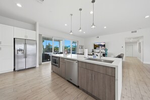 A modern kitchen with stainless steel appliances, a dishwasher, and a large island with a sink. - Luxury|Pickleball|Salt Water Pool/Spa (Scottsdale)