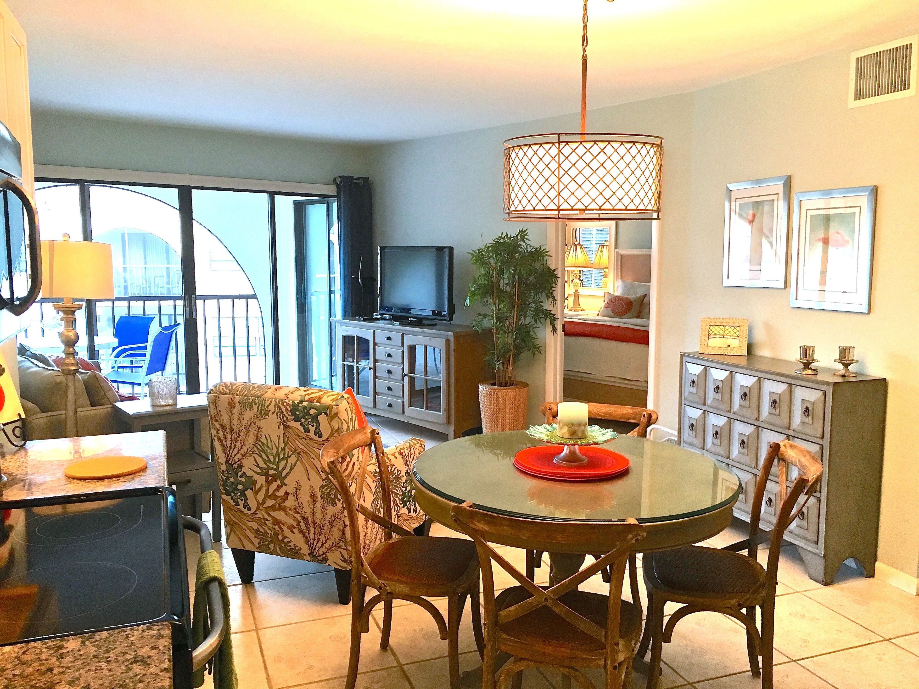 A dining area with a round table, chairs, a television, and a potted plant.
