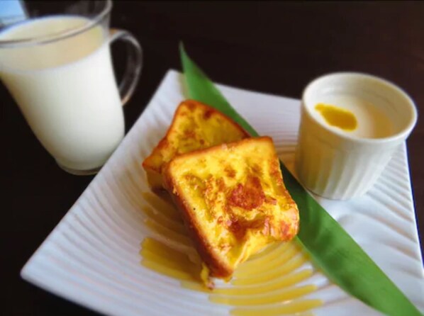 A plate with toast and a small cup of butter, and a glass of milk.