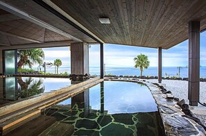 Une piscine à débordement offrant une vue imprenable sur l’océan et les palmiers.