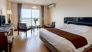 Une chambre d’hôtel avec un grand lit, un bureau avec une lampe, une chaise, une télévision et une fenêtre avec des rideaux.